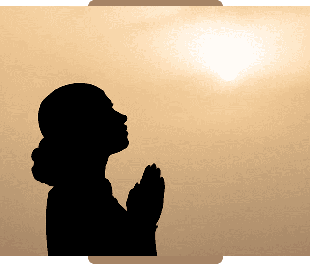 Woman in prayer against sun backdrop