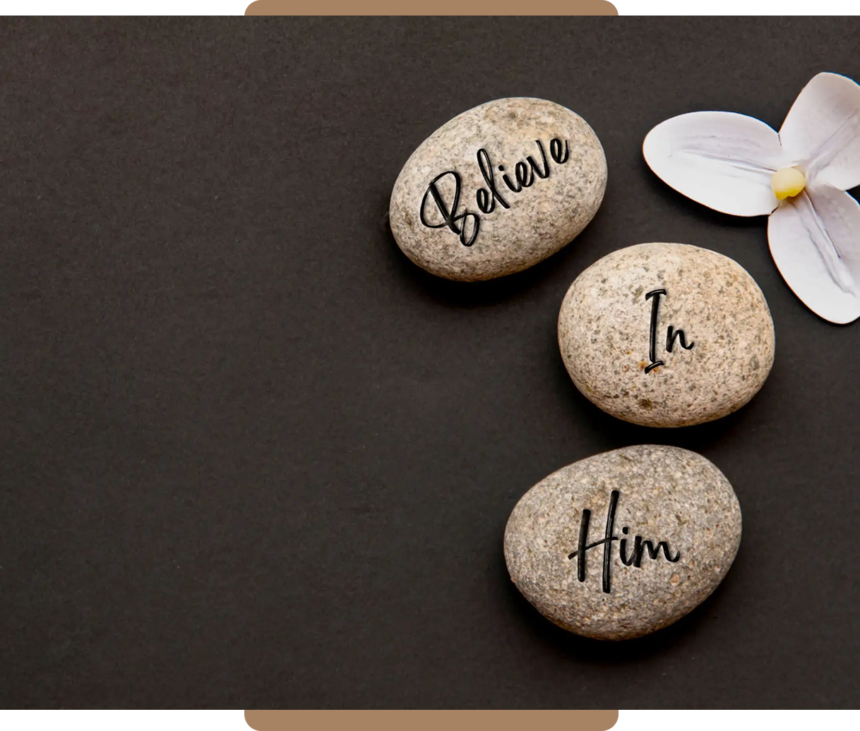 Three stones with words "Believe In Him" on a dark background.